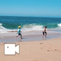 Dois meninos e um adulto estão brincando na praia.