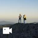 A couple stands atop a mountain