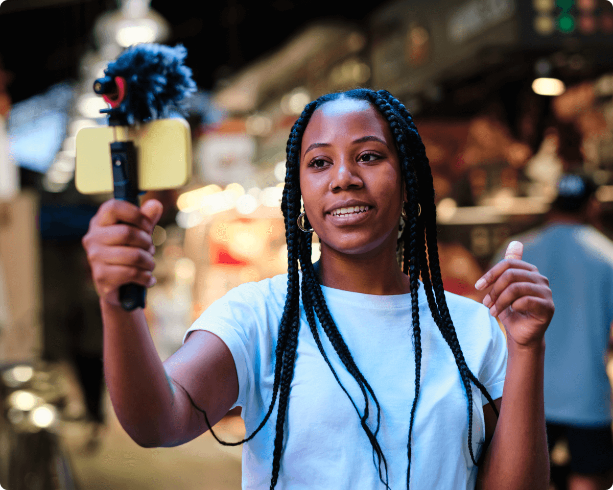 a woman with dreadlocks records video on her cell phone